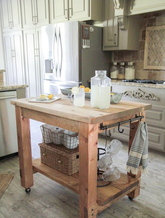 a rustic wooden kitchen island on casters with holders and hooks plus a storage space underneath