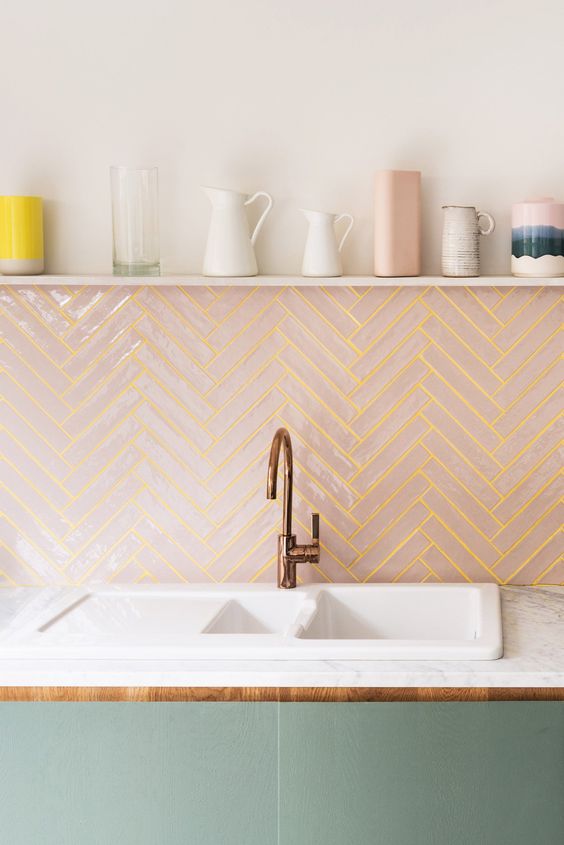 Blush tiles clad in a chevron pattern and spruced up with sunny yellow grout for a modern backsplash