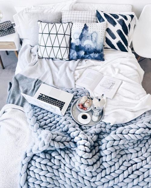 bright printed pillows and a matching powder blue chunky knit blanket for a welcoming bedroom