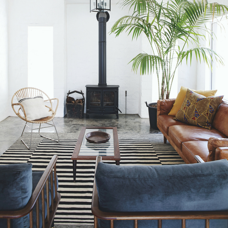 The living room features African aesthetics and modern comfy furniture, look at that vintage hearth