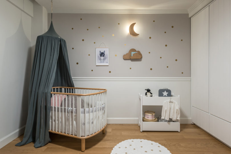 The nursery is a peaceful space done in neutrals, with little gold accents and a slate grey canopy for a touch of color
