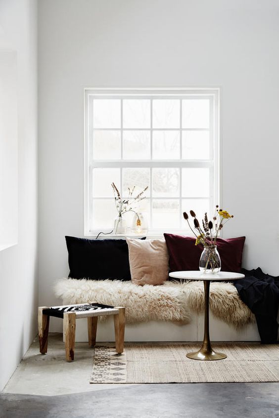 a cozy nook with a blush, plum and black velvet pillow, faux fur and a dried floral arrangement is a truly fall space