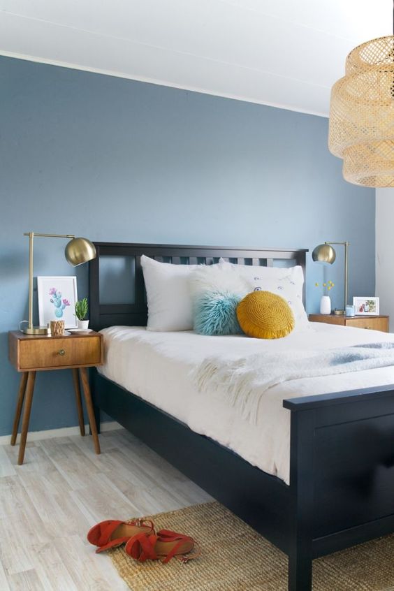 a slate blue accent wall and mustard touches add color to the mid-century modern bedroom