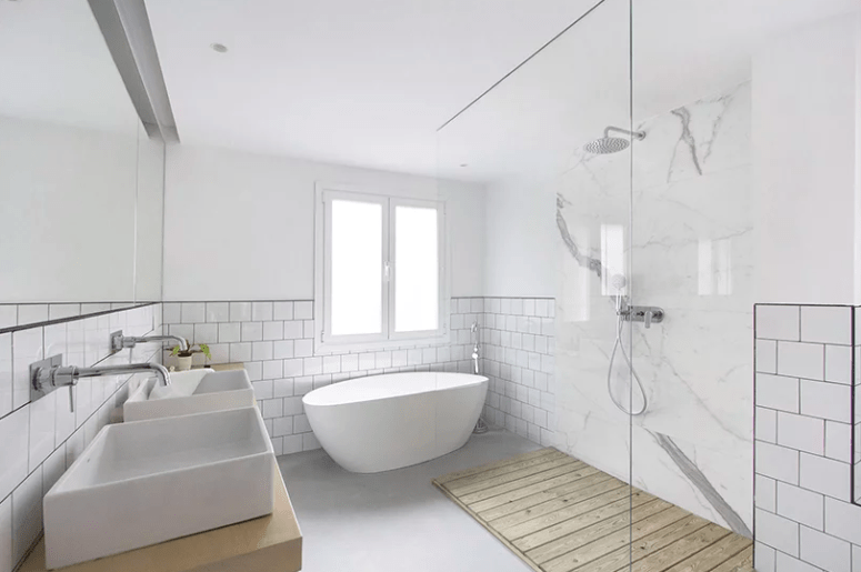 The bathroom is done with tow sinks, an oval bathtub and a minimalist shower done with marble and wood