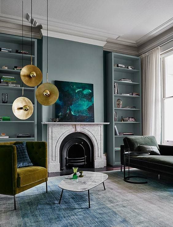 A bold emerald artwork and gilded pendant lamps over the mustard chair make the space fall like
