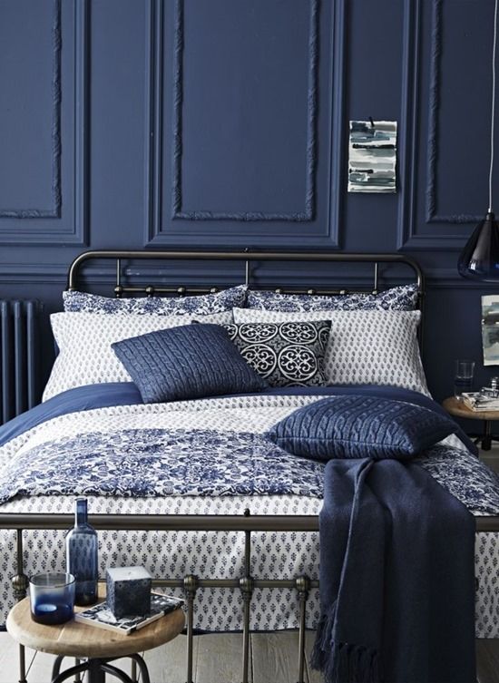 a dark blue wall with wainscoting and matching pillows for a relaxing moody space