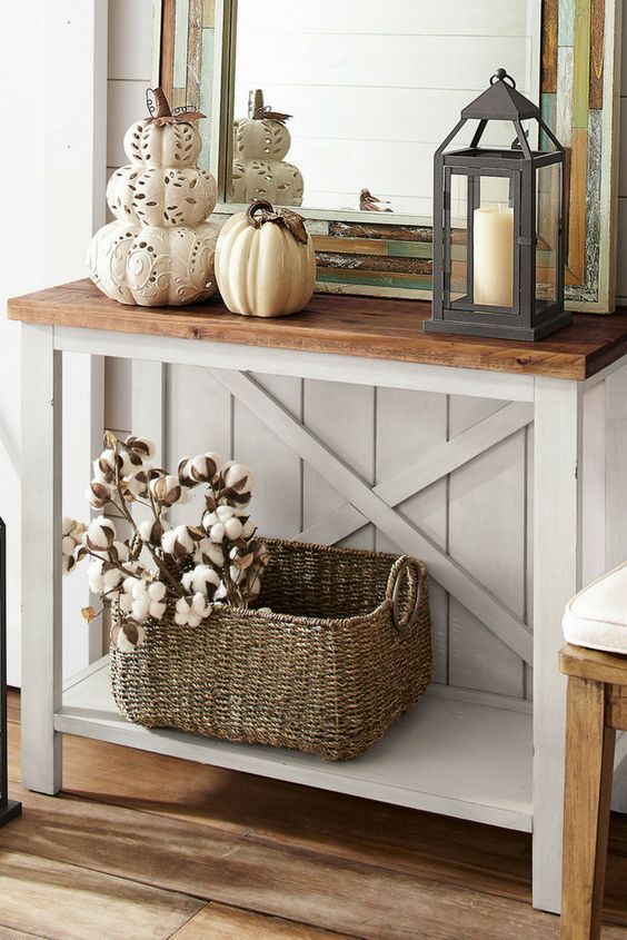 a vintage rustic console with laser cut pumpkins and a porcelain one, a candle lantern and a basket with cotton branches