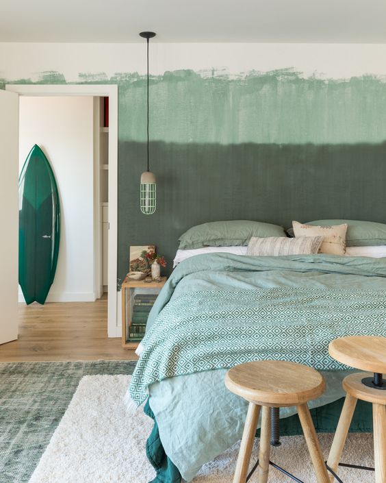 an ombre green statement wall and green printed bedding for a relaxing and comforting feel