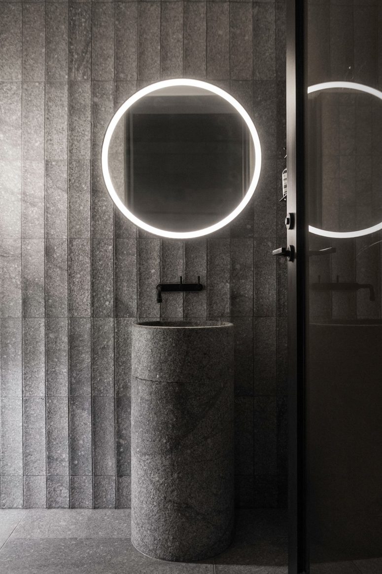 The sink is a free-standing stone one, and the mirror is lit up
