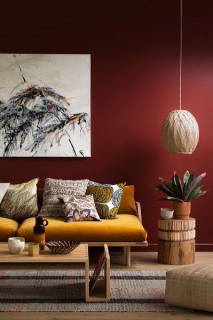 a stylish living room with a burgundy accent wall as a dominant feature and a saturated yellow sofa