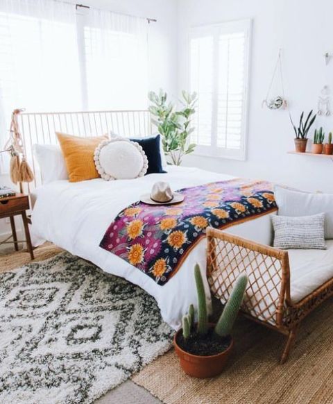 a wicker bench at the foot of the bed, colorful bedding and large tassels hanging