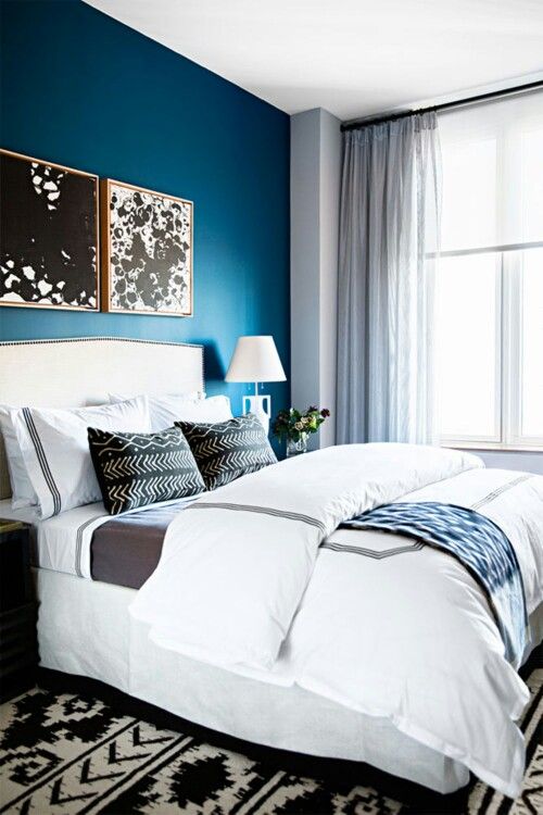 a monochromatic bedroom is infused with color - a bold blue accent wall that makes it vivacious