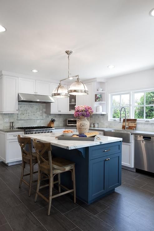 a beautiful white kitchen with a navy kitchen island and a marble countertop for a chic touch