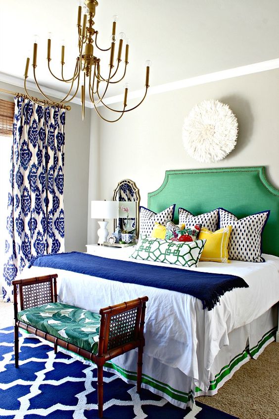 a bright green upholstered bed and a bold rattan bench with a palm leaf print