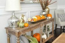 11 a rustic console table with pumpkin arrangements, pillows, blankets and dried blooms