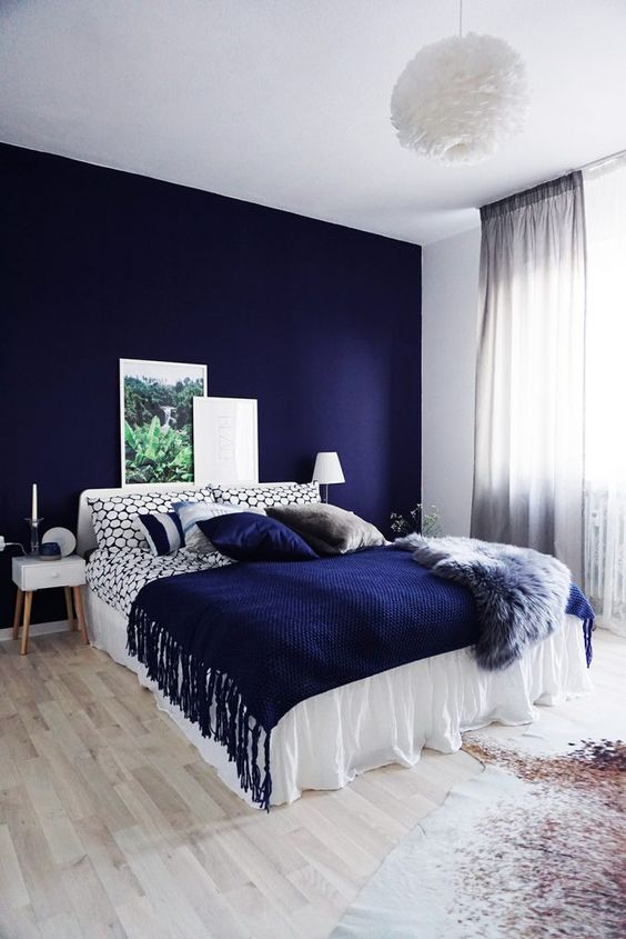 a bold blue accent wall plus a matching pillow and a fringed blanket for a wow effect
