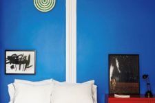 12 a bright red dresser in front of a blue wall make up a bold color combo for this bedroom