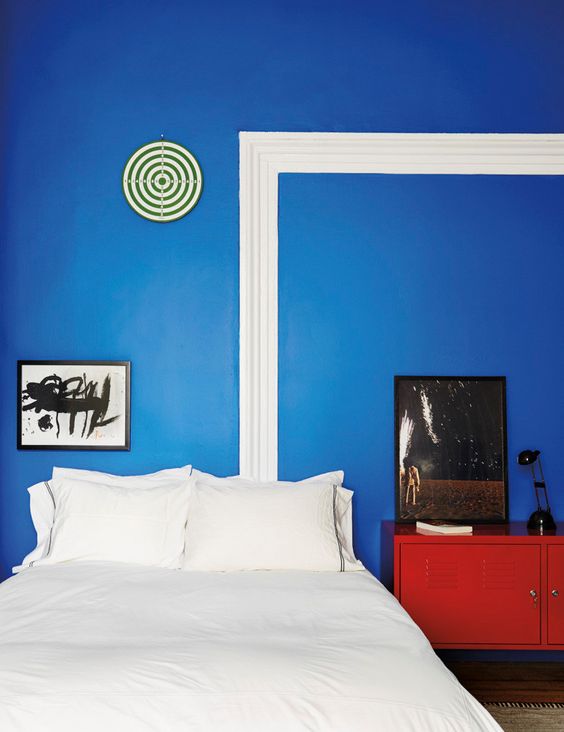 a bright red dresser in front of a blue wall make up a bold color combo for this bedroom