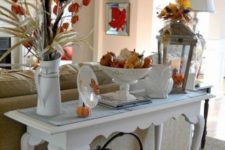 12 a refined console table with colorful pumpkins, fall leaves, porcelain and a metal basket with pumpkins