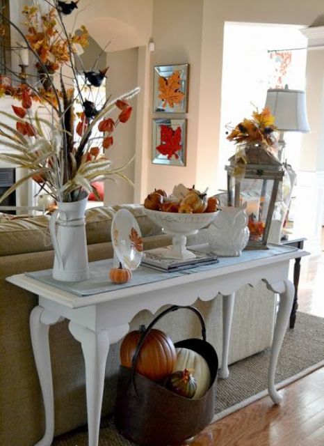 a refined console table with colorful pumpkins, fall leaves, porcelain and a metal basket with pumpkins