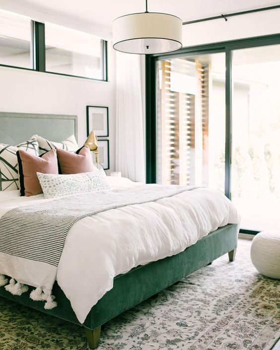 a green upholstered bed and matching framing of the windows and doors for a bold look