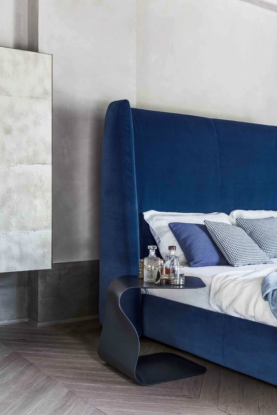 a bold blue upholstered bed with a tall curved headboard is a chic idea for a contemporary space