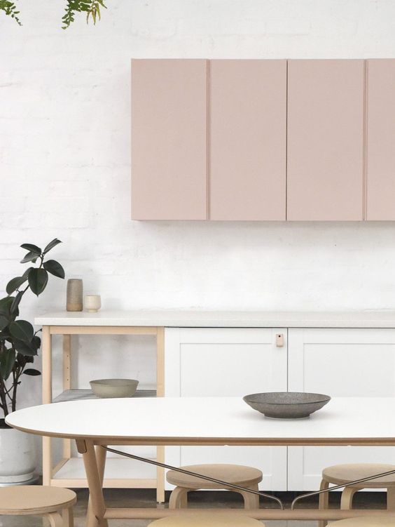 A chic contemporary kitchen with white and blush cabinets shows off the two tone trend