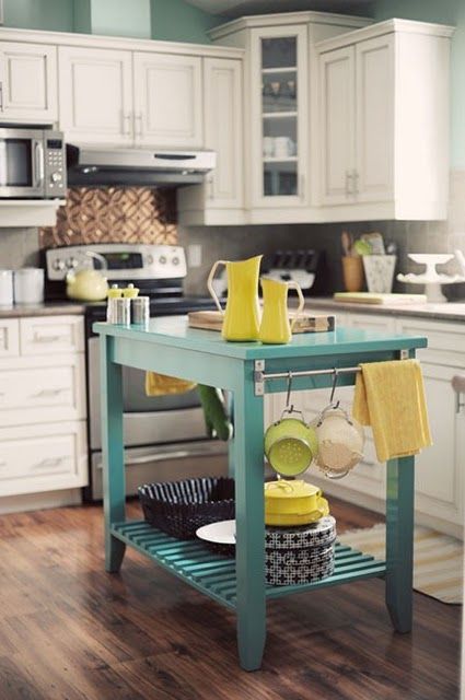 a bright turquoise kitchen island with a shelf and some holders adds color to the space