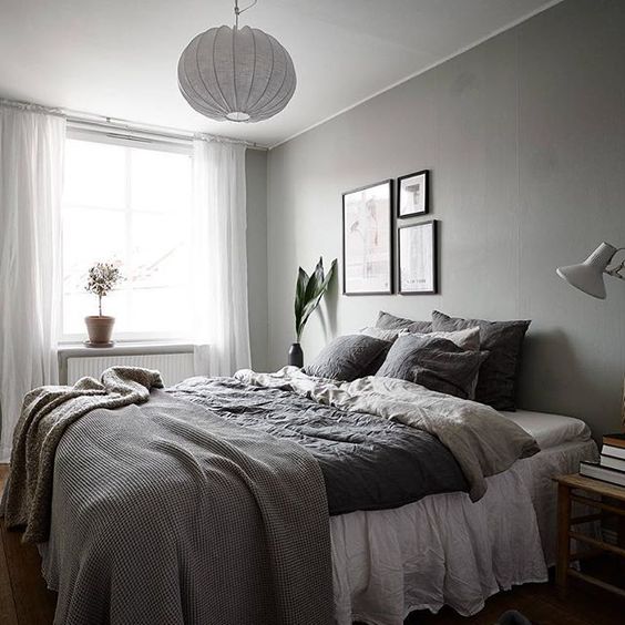 a bedroom in various shades of grey spruced up with a small monochromatic gallery wall over the bed