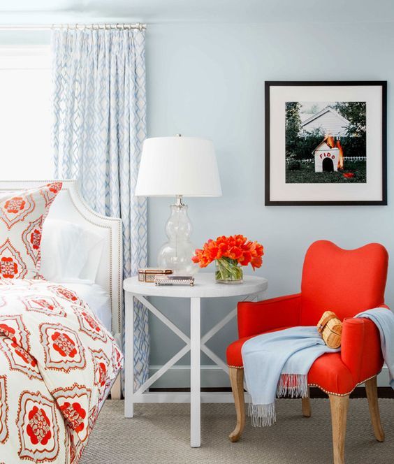 a hot red chair on wooden legs adds to the powder blue coastal bedroom