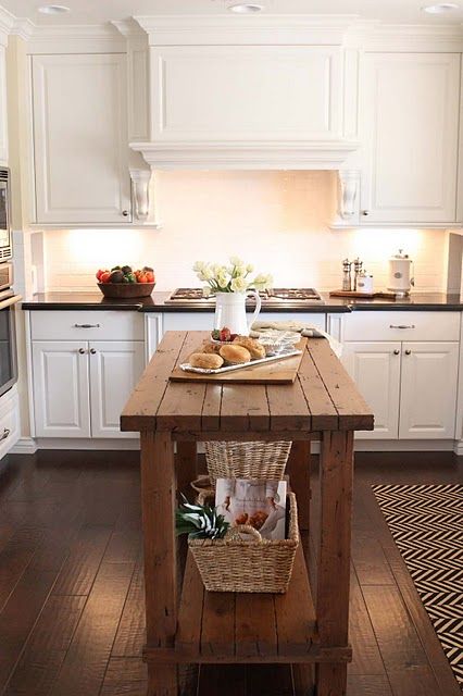 a rustic wood kitchen island contrasts white cabinets and features storage space underneath