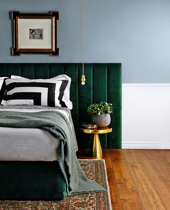 an upholstered emerald bed and a large headboard to add contrast and color to the space