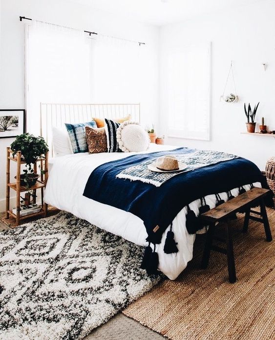 potted plants, bold boho pillows and a tassel bedspread are slight touches to make the space boho