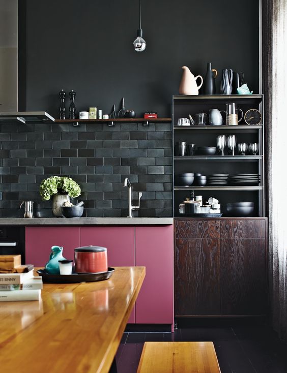 a moody kitchen in dark shades is spruced up with a bold pink cabinet and a bold stained table