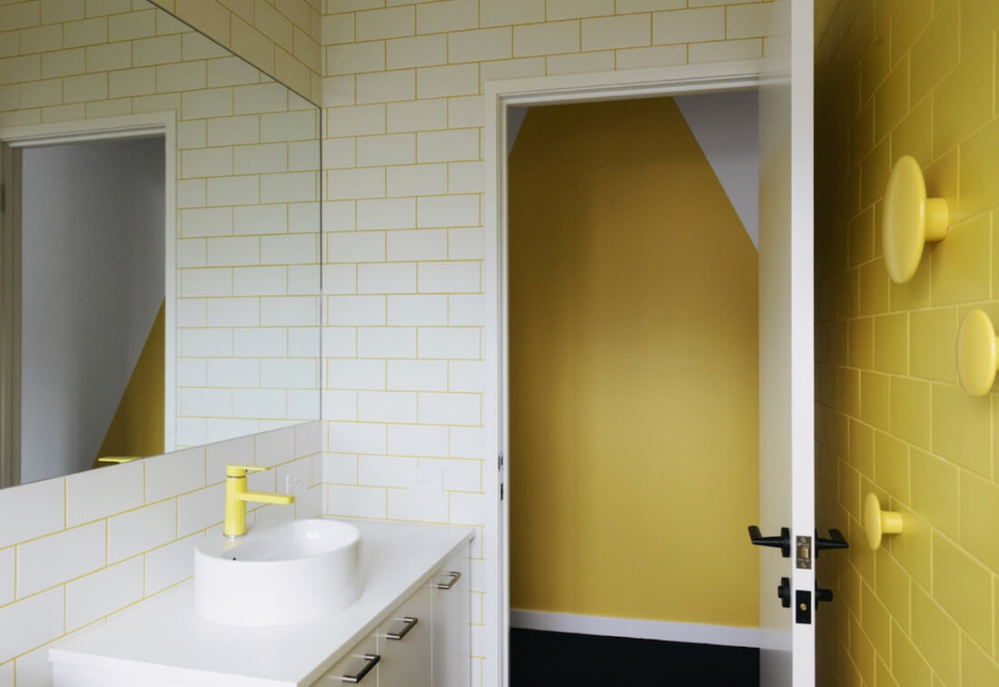 Neon yellow grout, fixtures and an accent tile wall with wall hooks, all in yellow