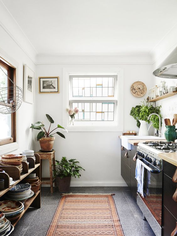 a boho chic kitchen with wooden touches and a boho rug plus potted greenery
