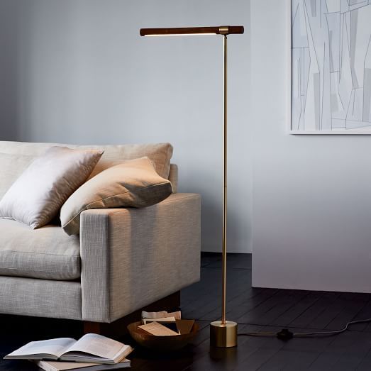 an elegant minimalist floor lamp with a thin metal leg, a metal base and a wooden linear lampshade