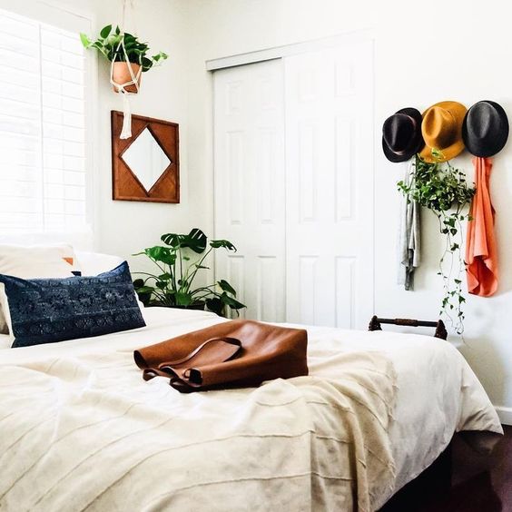 give a boho feelto your bedroom with some hats on the wall, potted greenery and boho bedding