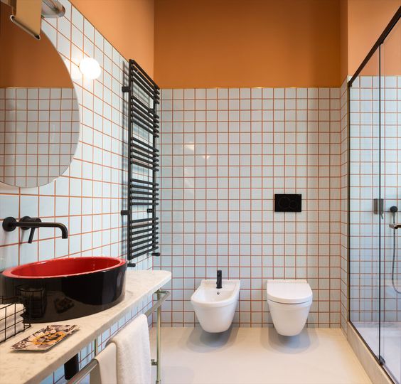 spruce up your bathroom with colorful grout like here with orange grout and orange half walls