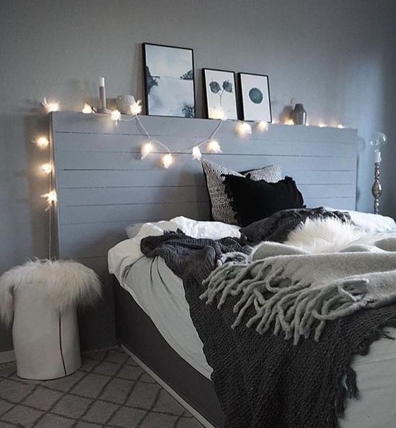 a grey bedroom spruced up with lights and a monochromatic gallery wall, black bedding