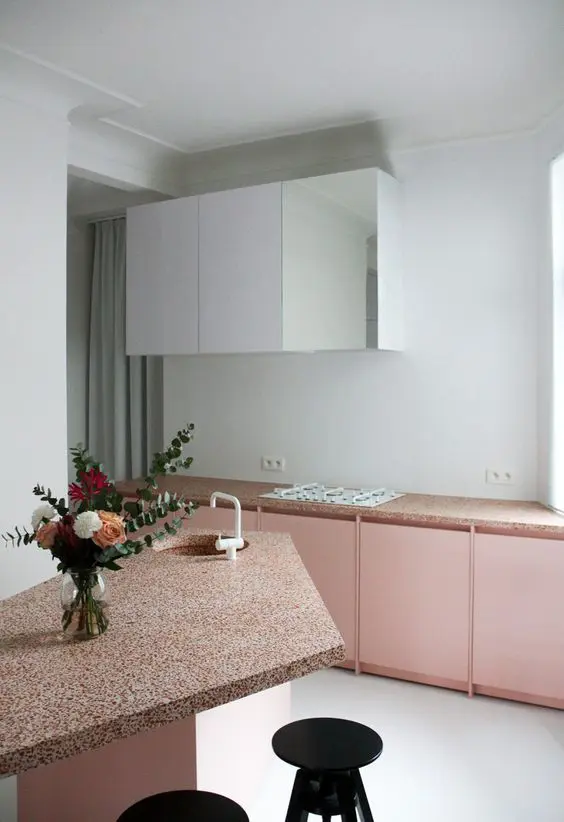 Blush kitchen cabinets with terrazzo countertops and white upper cabinets for a trendy look