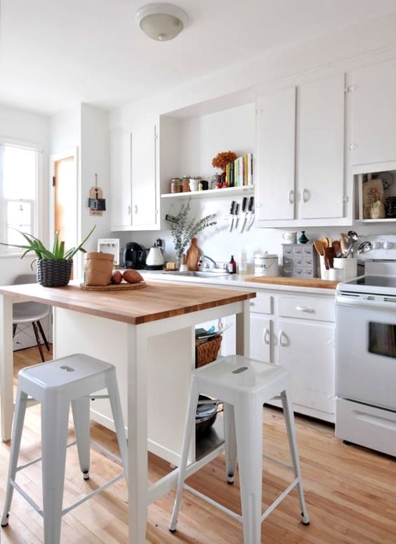 a small white kitchen island with storage shelves and a meal zone with stools