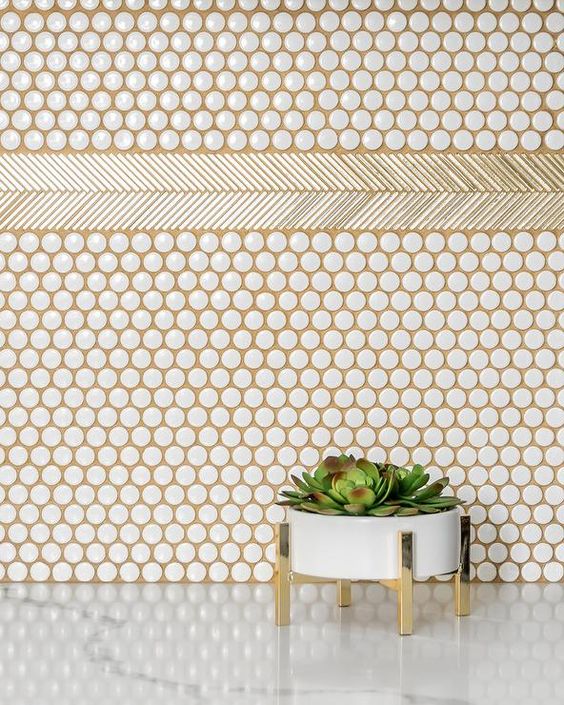 white penny tiles spruced up with gold grout and a planter on gold legs for an accent