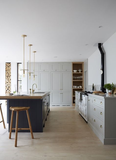 vintage-inspired grey cabinets and a navy kitchen island in the same style with a wooden countertop for a chic look