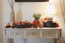 25 a vintage rustic console table with baskets, fall leaves, pinecones, corn cobs and greenery in a vase