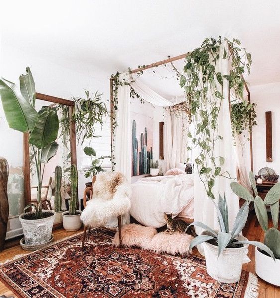 a boho rug, lots of greenery and cacti, faux fur and a canopy bed for a welcoming boho bedroom