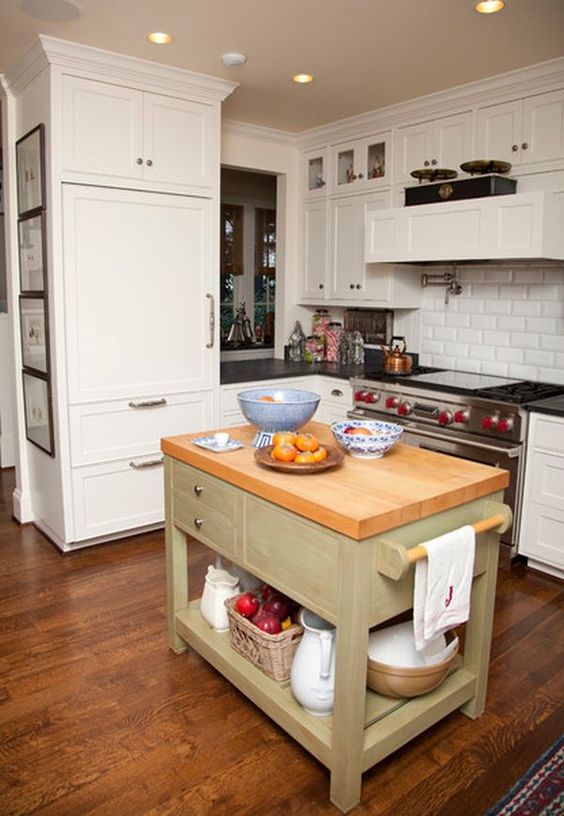 an olive green kitchen island with a wooden countertop, drawers and open storage in rustic style