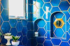 26 bright blue hexagon tiles with gold grout that highlights the gold fixtures and creates a contrast
