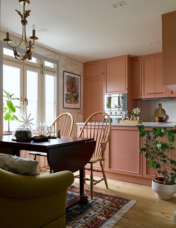 A beautiful peachy pink kitchen with a kitchen island and built in appliances plus a dining zone with a folding table