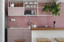 a catchy kitchen with a pink tile backsplash and pale pink cabinets, open shelving and a large white kitchen island